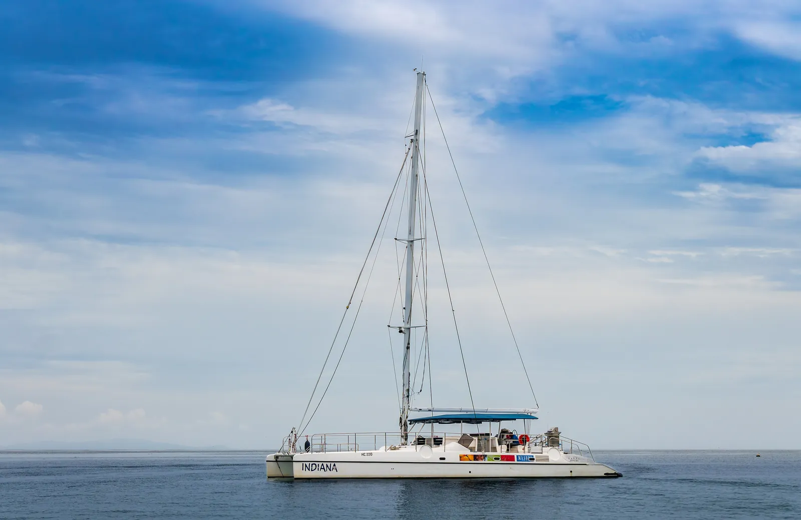 Un catamarano a vela all'ancora, con il mare calmo e il cielo azzurro
