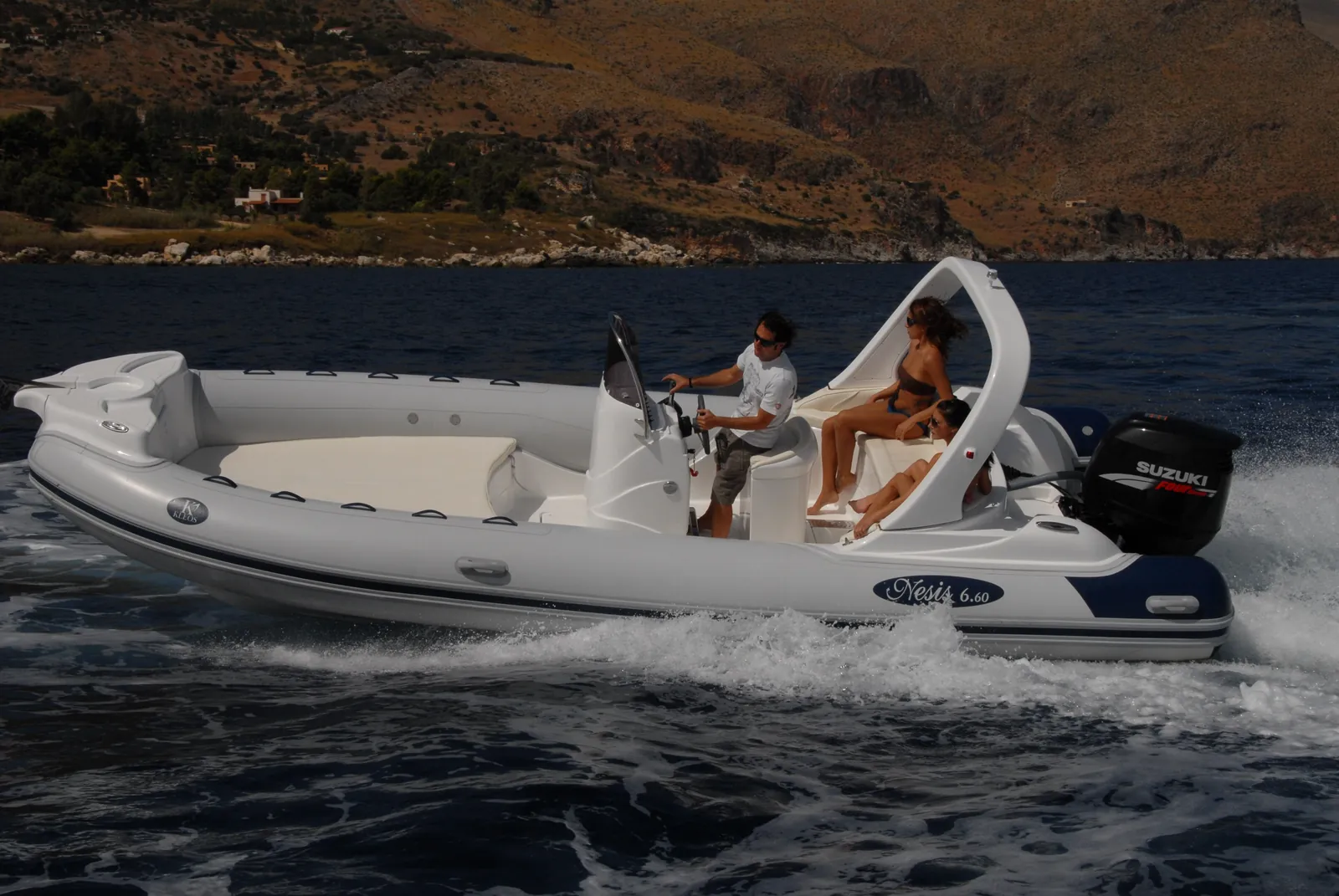 Un gommone con due persone a bordo naviga veloce sotto costa
